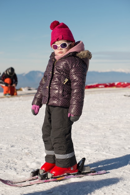 Счастливая маленькая девочка на лыжах под гору