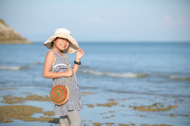 幸せな少女は笑顔し、海の背景に帽子をかぶる