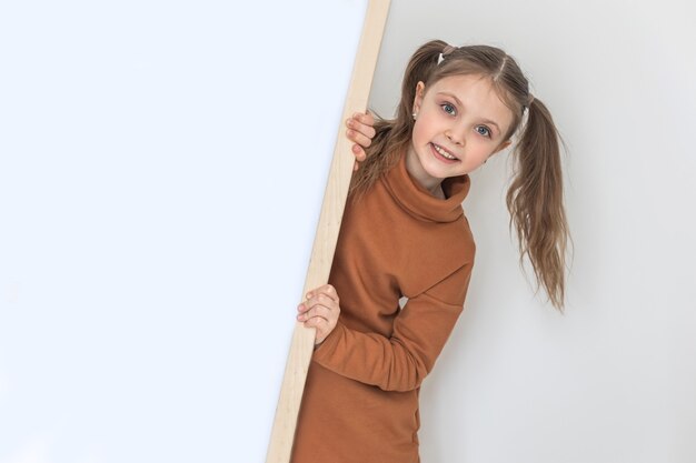 Happy little girl smiling and holding an empty drawing board