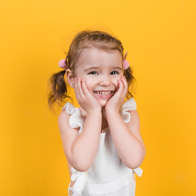 Foto bambina felice che sorride sulla priorità bassa gialla