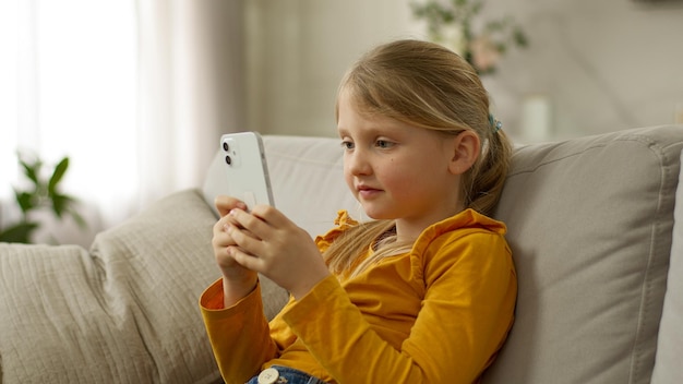 スマートフォンを持った幸せな女の子 ソファ 幸せなニュース 勝利 興奮