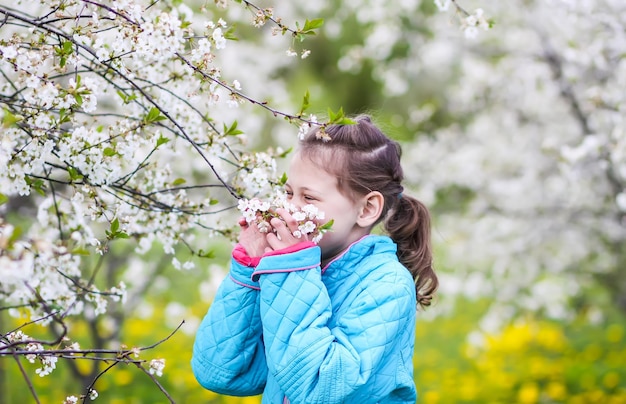 Happy little girl in a spring garden with blooming cherry trees