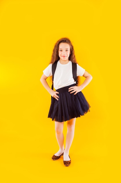 The happy little girl stands on a yellow background