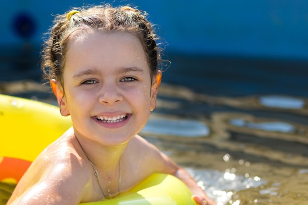 Una bambina felice che nuota in un anello gonfiabile colorato