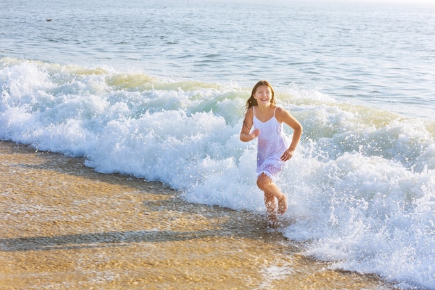 물 해변에서 수영하는 행복한 어린 소녀 바다에서 노는 소녀