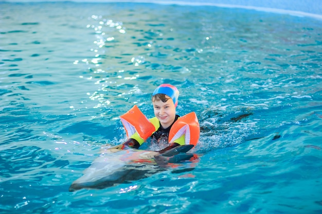 Happy little girl swimming with dolphins in dolphinarium.