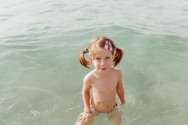 Happy little girl swims in sea Summer and vacation concept