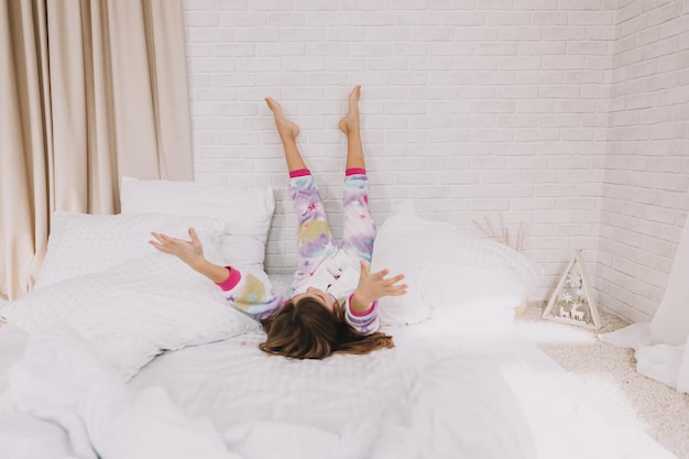 Foto la bambina felice getta il cuscino a letto a casa