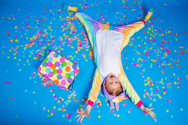 A happy little girl in a unicorn kigurumi holds a gift bag