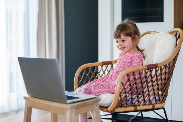 Счастливая маленькая девочка разговаривает по видео с бабушкой и дедушкой, используя ноутбук