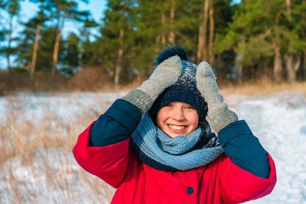 Happy little girl walking in winter forest in sunny day