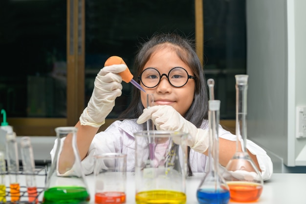 Happy little girl wearing lab coat making experiment