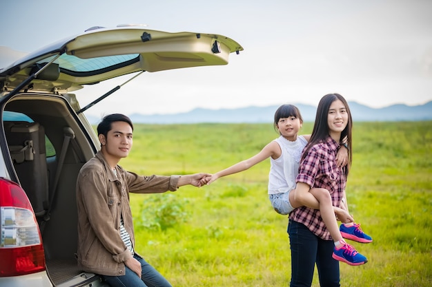 Bambina felice con la famiglia asiatica che si siede nell'automobile per godere del viaggio stradale e delle vacanze estive io