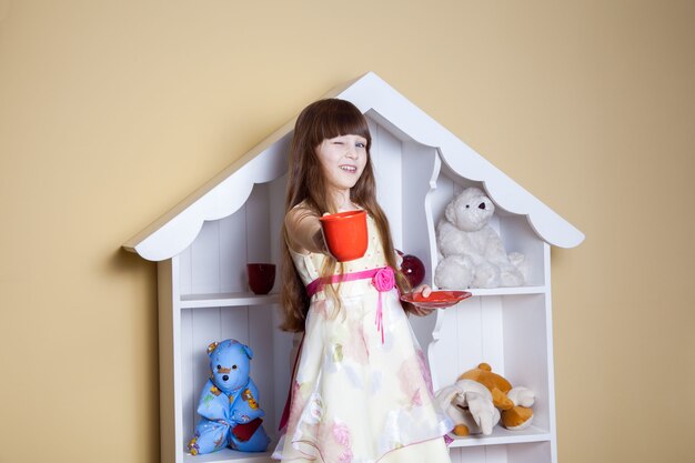 Happy little girl with cup of tea in her room