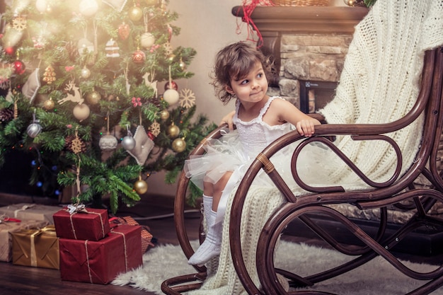 Счастливая маленькая девочка с подарками в красивых коробках в рождественском интерьере