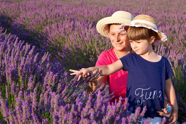 彼女の母親と一緒に幸せな少女はラベンダー畑にいます