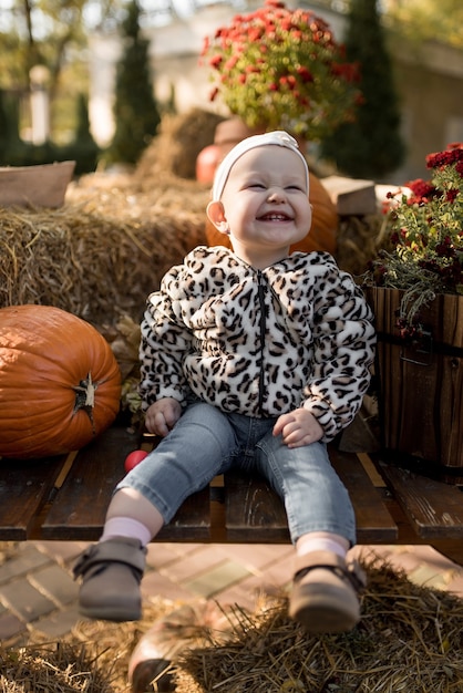 가을 공원에서 호박을 든 행복한 어린 소녀는 웃는다