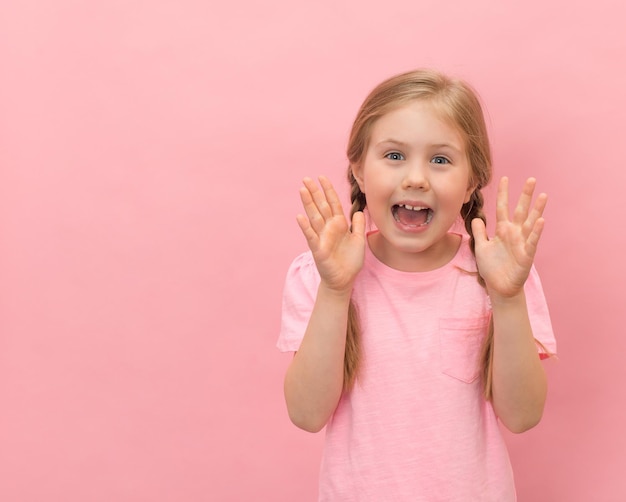 Happy little girl yelling with hand near her mouth on pink background