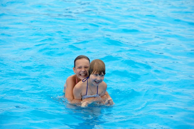 Happy little girls have fun swimming in the pool