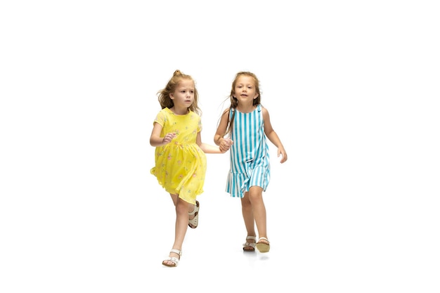 Happy little girls jumping and running on white background, childhood