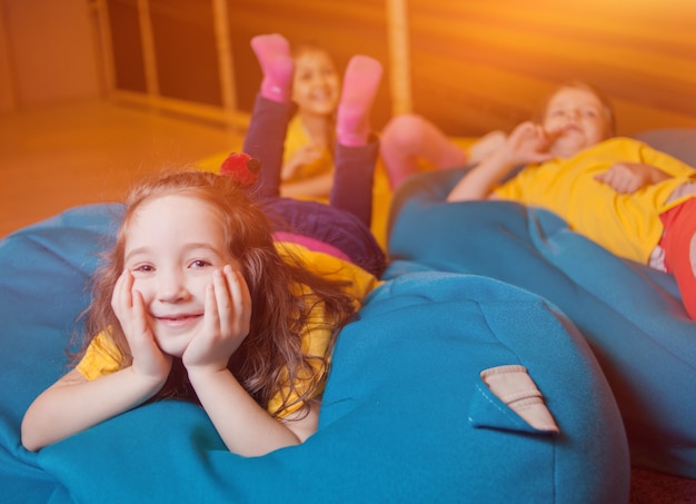 Happy little girls lie on the chair bag in the children's entertainment center