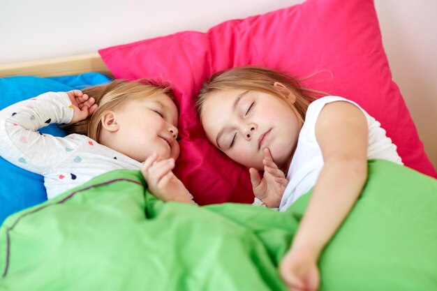 Photo happy little girls sleeping in bed at home