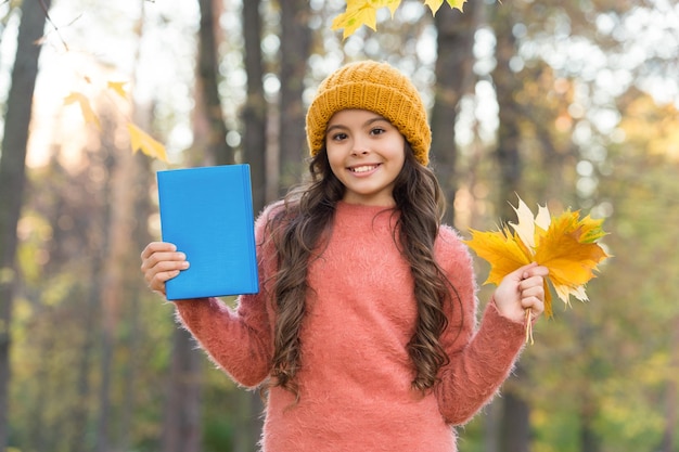 Happy little kid collect autumn leaves holding school book fall season outdoors imagination