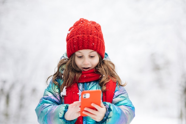 幸せな小さな子供はスマートフォンの面白いフェイスマスクアプリを使用して、セル画面の笑顔を見て面白いものを見てください。