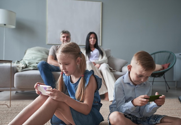 Happy little kids brother and sister use phones at home