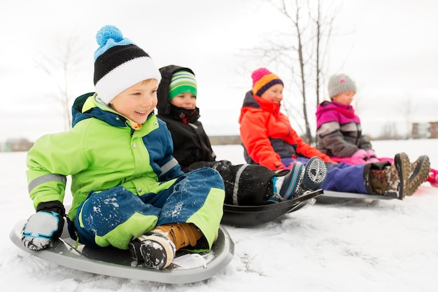 Foto bambini felici che scivolano sulle slitte in inverno