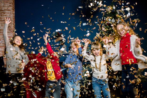 Bambini piccoli felici lanciano coriandoli e festeggiano il natale