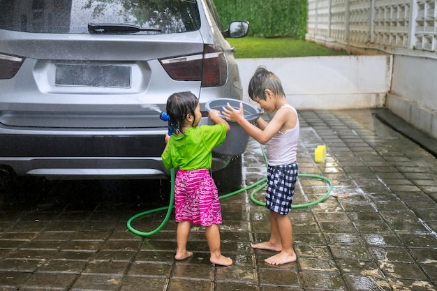 Happy little kids washing a car at home