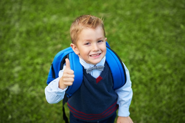 Happy little preschool kid boy with backpack posing outdoors