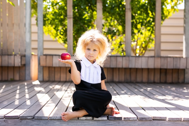 Happy little schoolgirl with apple. Back to school outdoor