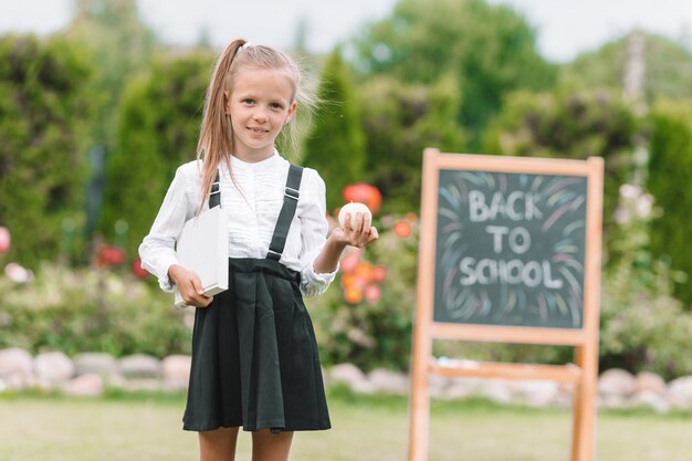 Happy little schoolgirl with a chalkboard outdoor