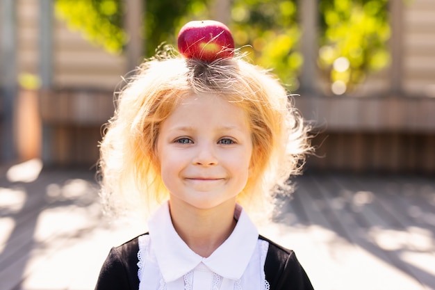 Happy little schoolgirl with lunch, book and pencils. Back to school outdoor