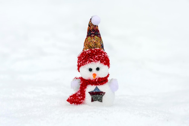 Happy little snowmen in red blue cap and scarf standing in winter snow background