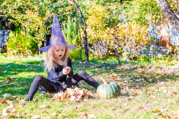 Happy little witch have fun outdoors on Halloween. Trick or treat.