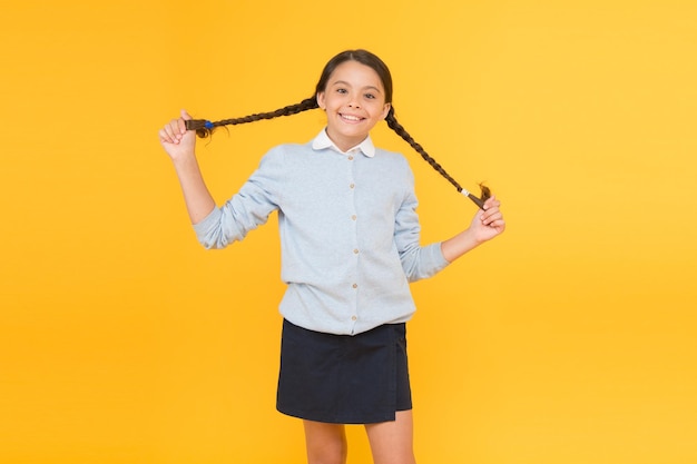 Happy look smart little girl on yellow background knowledge day childhood happiness happy girl in school uniform kid fashion school market education concept back to school