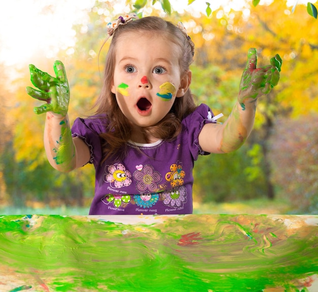 Happy looking kid playing with paints in his fingers.