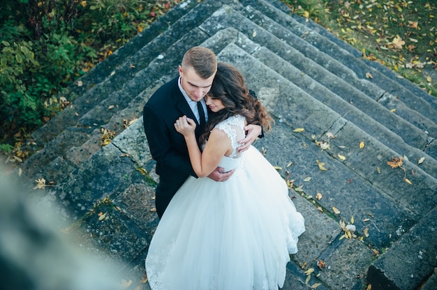 Happy and in love bride and groom walk in autumn park on their wedding day