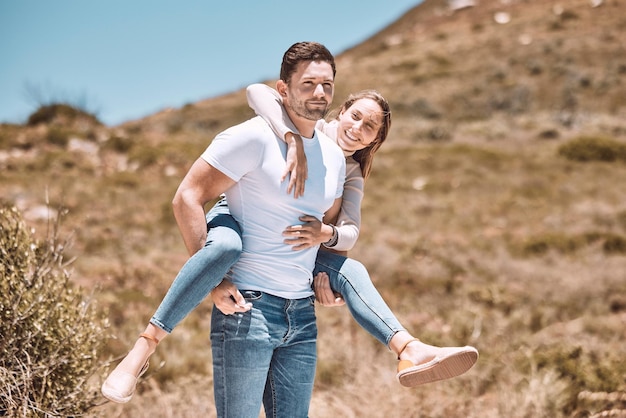 Happy and in love couple having fun in nature and enjoying quality time together Cute and relax boyfriend piggyback or carrying girlfriend with a smile on a bonding and romantic countryside date