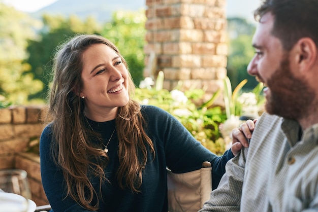 Happy love and couple on a patio smile and relax laughing and bonding with joke and conversation outside Family woman and man enjoying relationship quality time and a quiet day in a yard