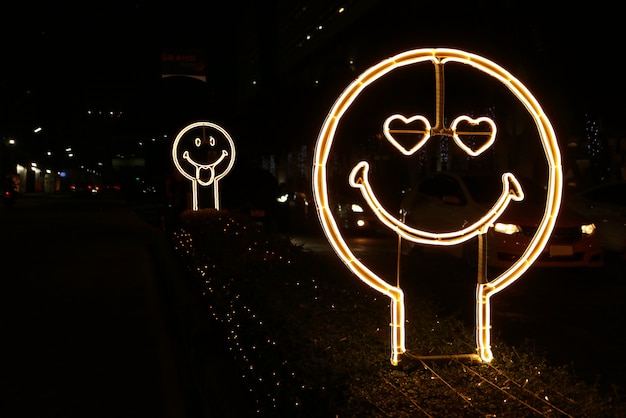 Happy and love face shaped neon light sign on the street side at night