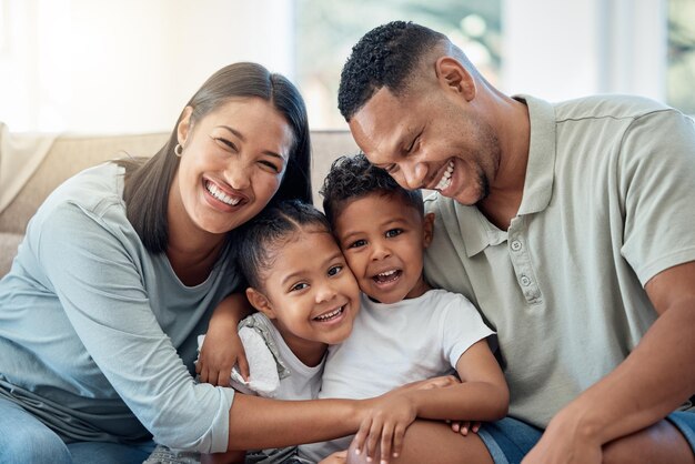 Happy love and family portrait with kids parents and relax on a sofa with a smile in the living room Happiness care and mom with dad sitting and holding children with joy on a couch in home