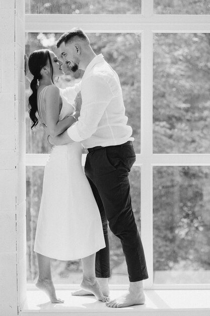 Happy lovely young couple standing at the window at home