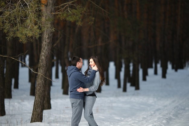 Happy lovers in winter on background of snowy forest outdoors