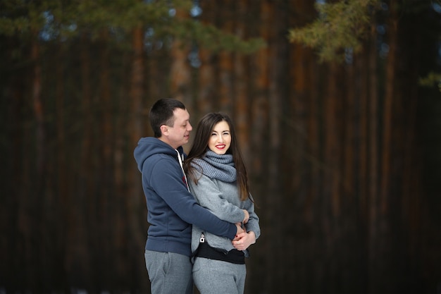 Happy lovers in winter on background of snowy forest outdoors