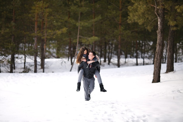 Счастливые влюбленные зимой на фоне заснеженного леса на открытом воздухе