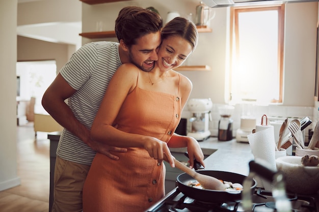 Photo happy loving and cooking couple bonding and having fun while spending time together at home playful fun and smilinghusband and wife hugging while preparing a meal and sharing a romantic moment